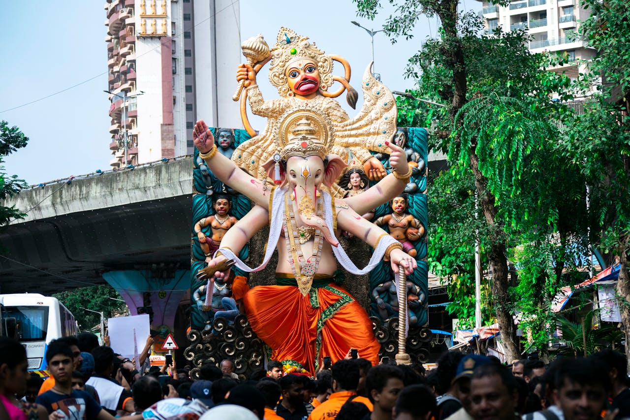 Crowds celebrate Ganesh Chaturthi with a large Ganesha statue in Mumbai streets.