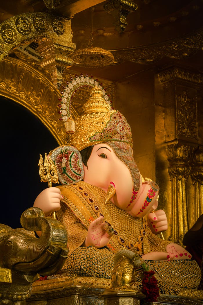 Beautifully decorated Ganesh idol adorned in gold, reflecting Indian cultural and religious artistry.